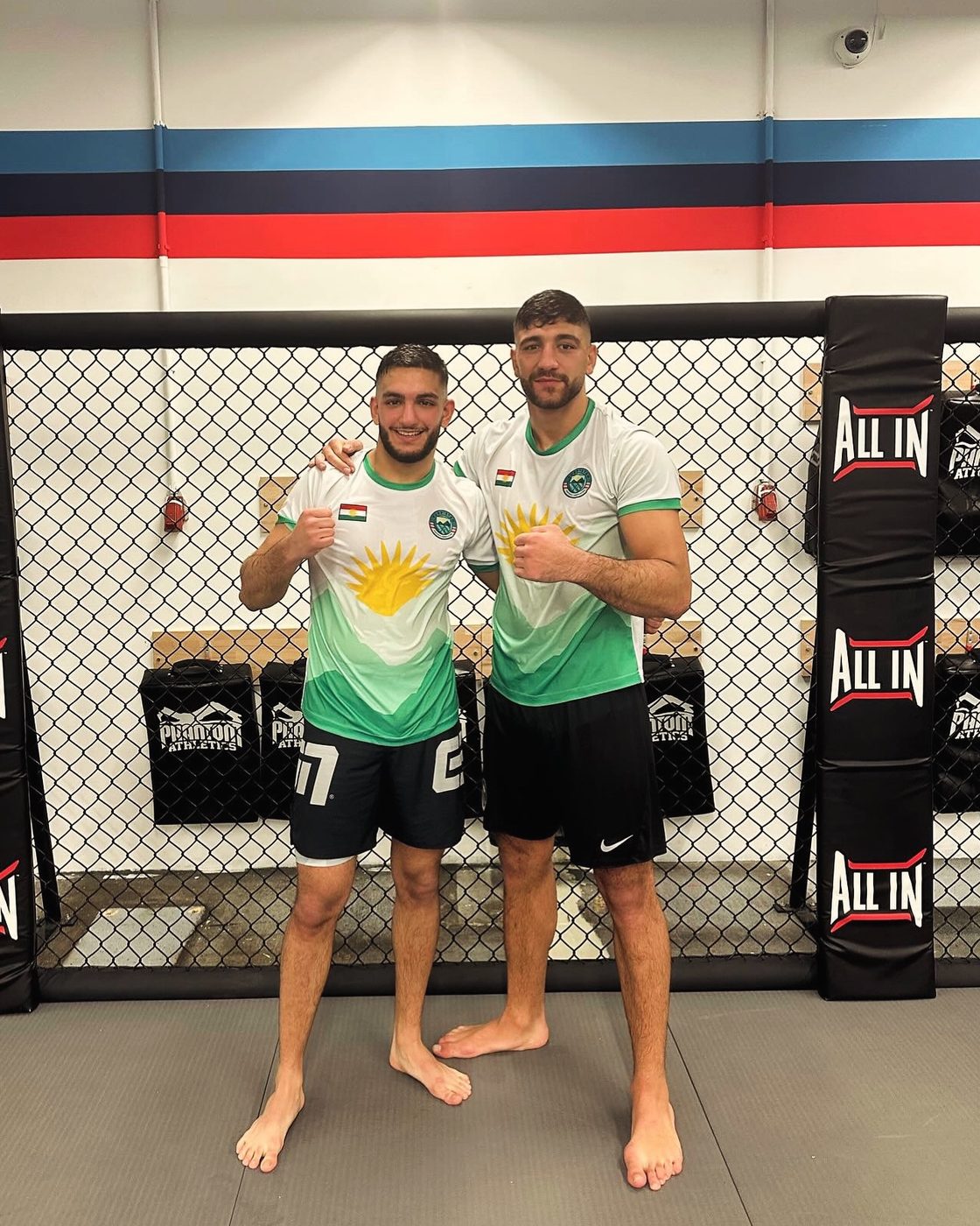 Zwei kurdische MMA-Kämpfer in Çiyayê Kurdî Shirts vor dem Käfig