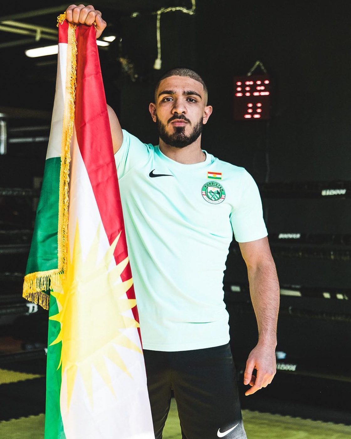 Kurdischer MMA-Kämpfer mit der Flagge Kurdistans in der Trainingshalle