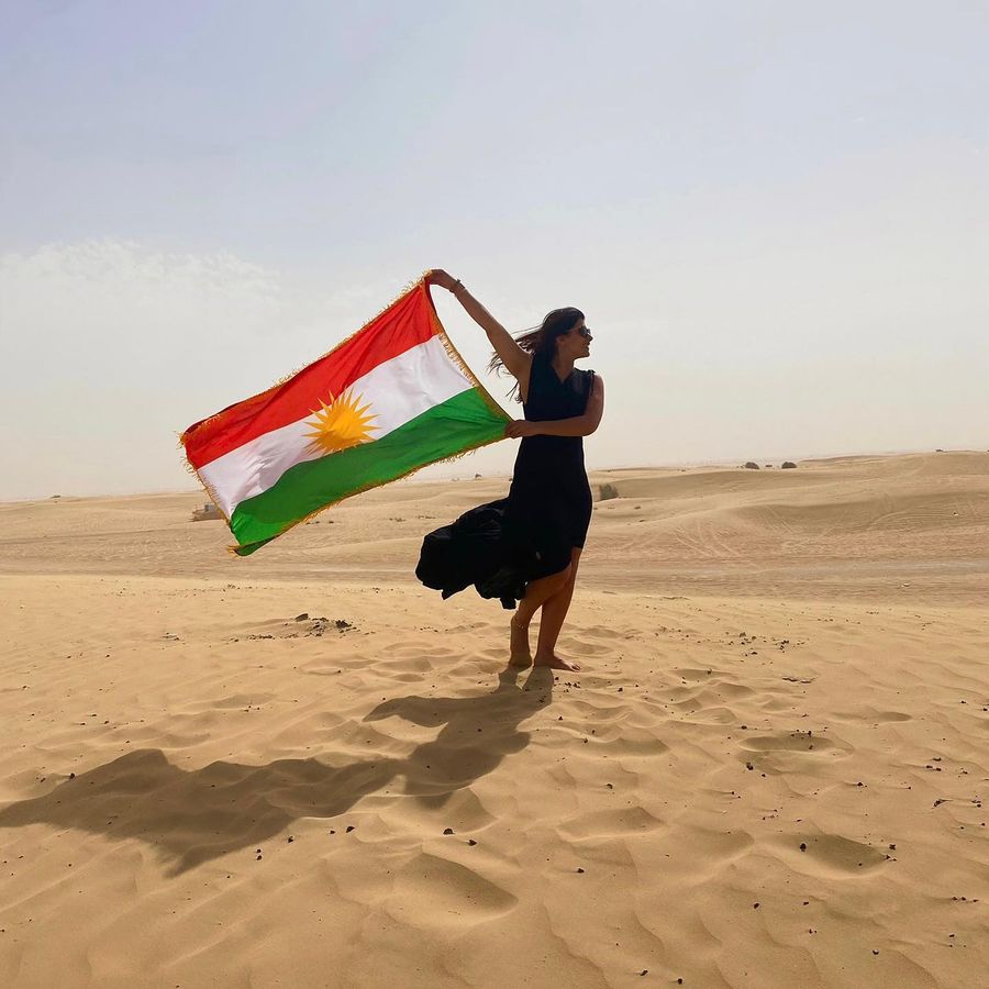 Kurdische Frau mit der Flagge Kurdistans in der Wüste