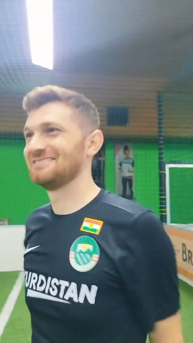 Junger kurdischer Mann lächelnd im Kurdistan Trikot auf dem Platz