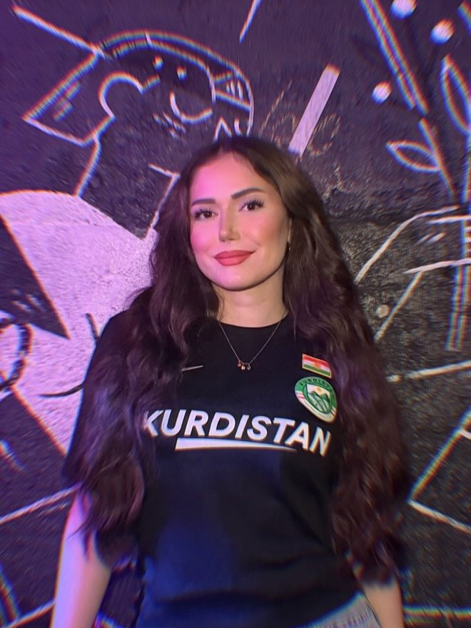 Junge kurdische Frau im schwarzen Kurdistan Nike Trikot vor einem Wandgemälde